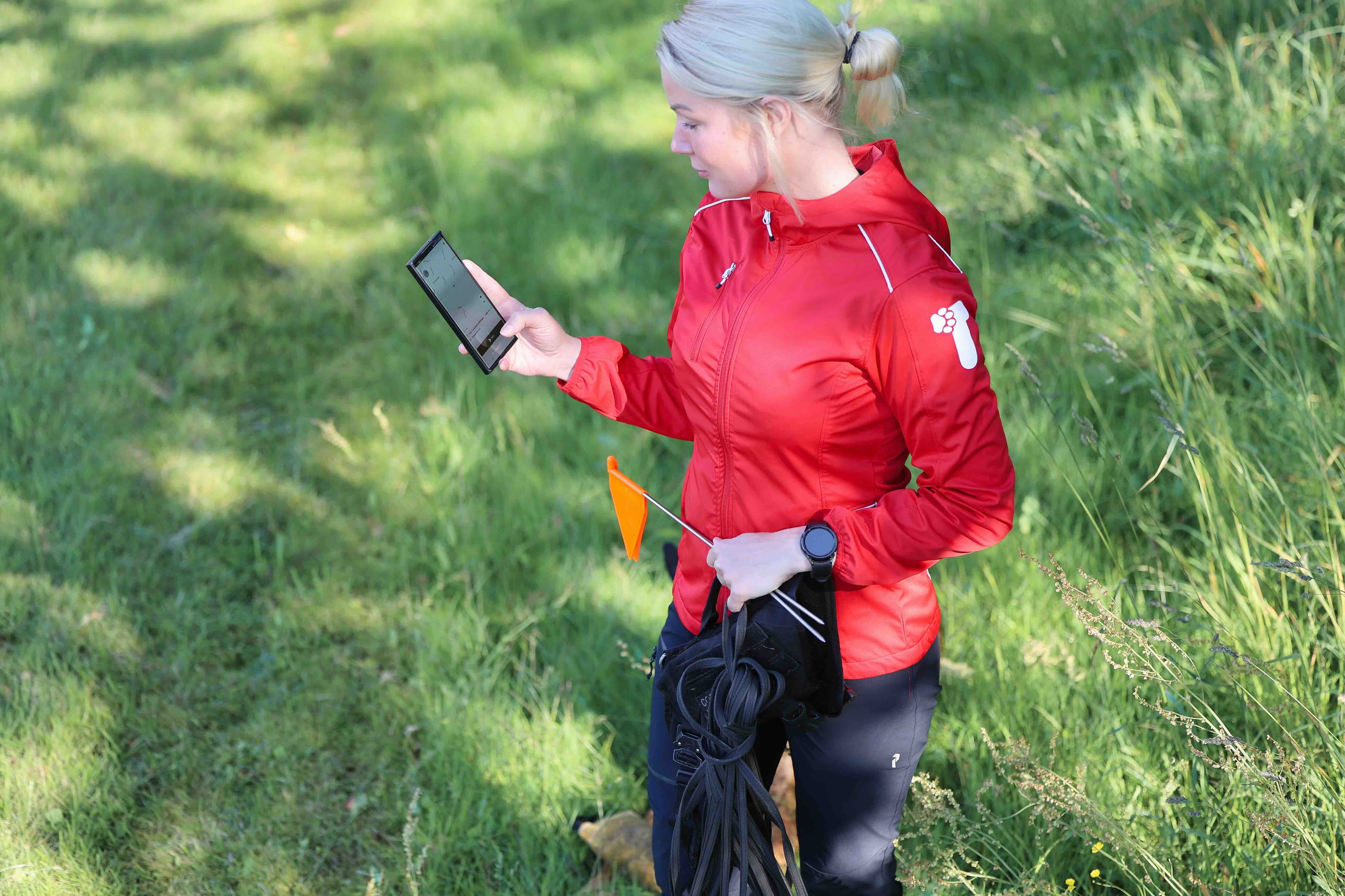 Jenna, founder of TrackFellow, crouched next to her working dog in a forest clearing.
