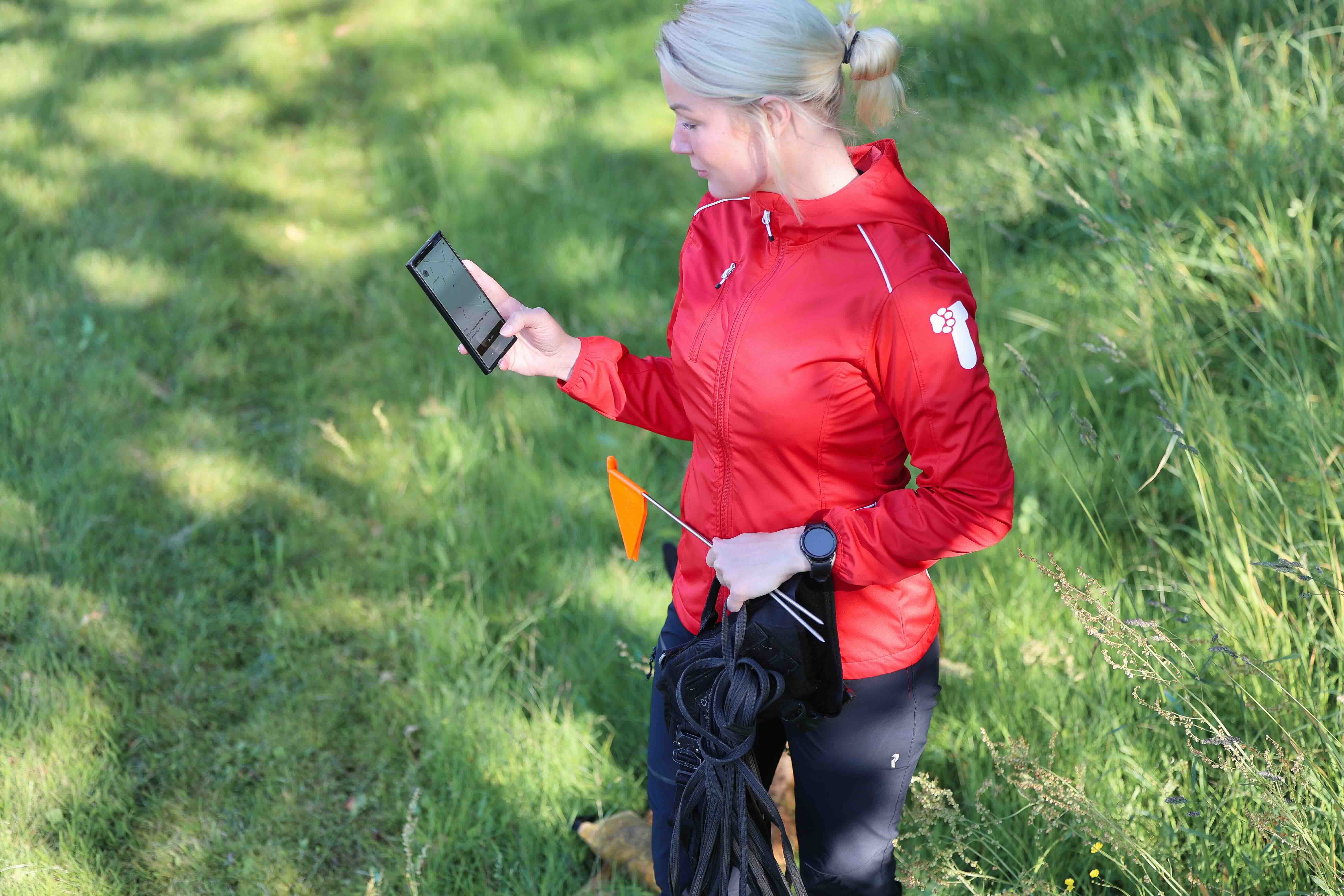 Jenna, founder of TrackFellow, crouched next to her working dog in a forest clearing.